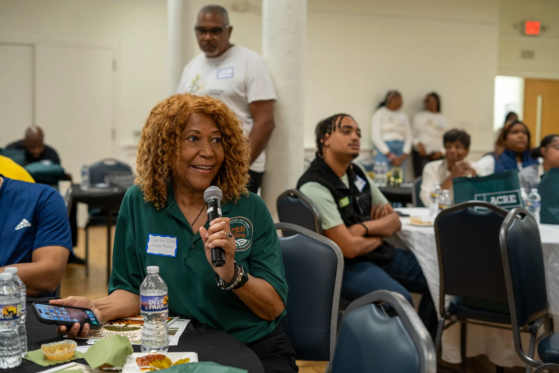 A speaker addresses people seated around tables.
